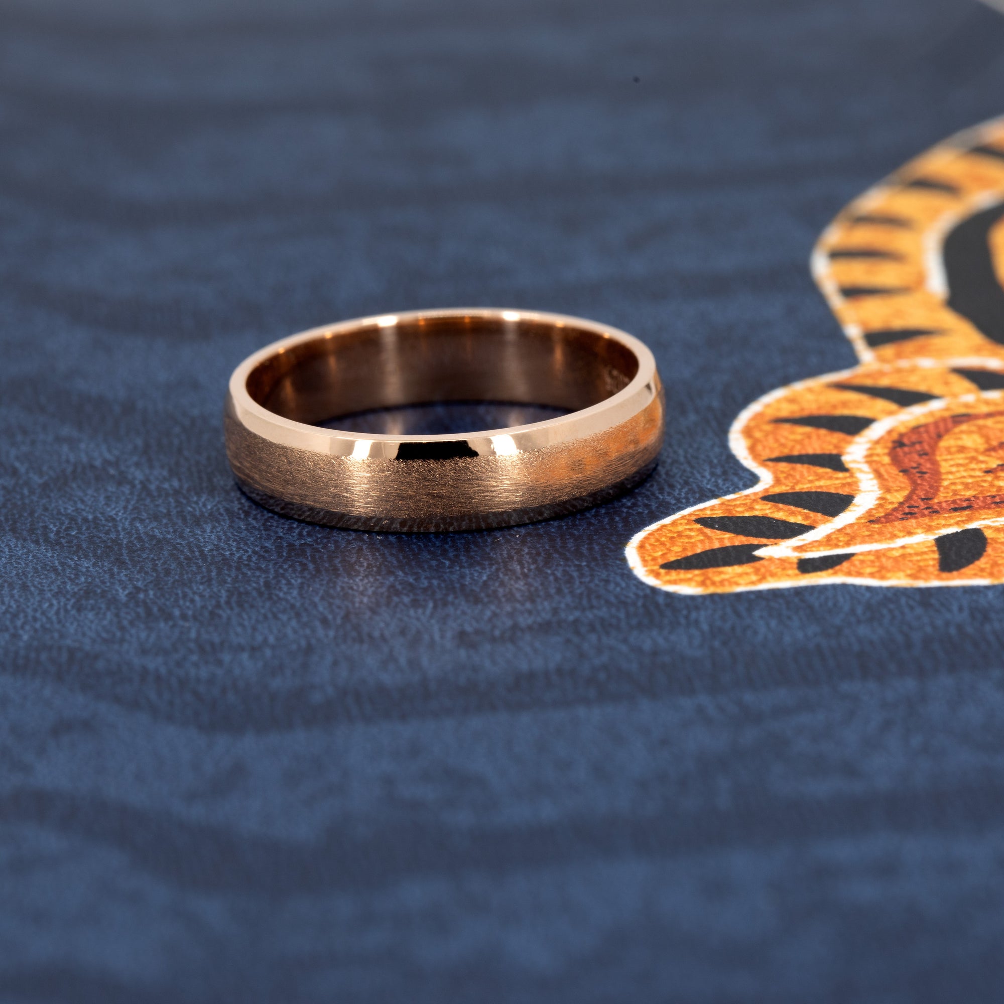 Rose gold wedding ring with a minimalist matte finish and polished details. Handmade by Bena Jewelry, showcased on a dark background for contrast.