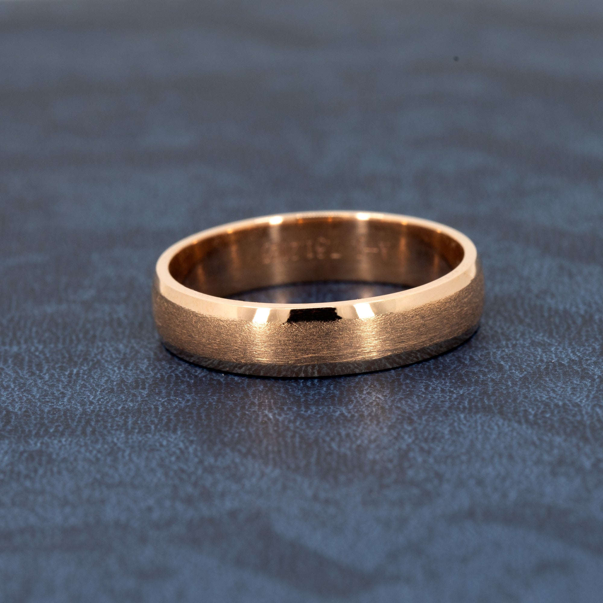 Men’s wedding band in solid rose gold, featuring a matte center and polished edges. Elegant and modern design by Bena Jewelry, photographed on a dark background.