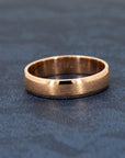 Men’s wedding band in solid rose gold, featuring a matte center and polished edges. Elegant and modern design by Bena Jewelry, photographed on a dark background.