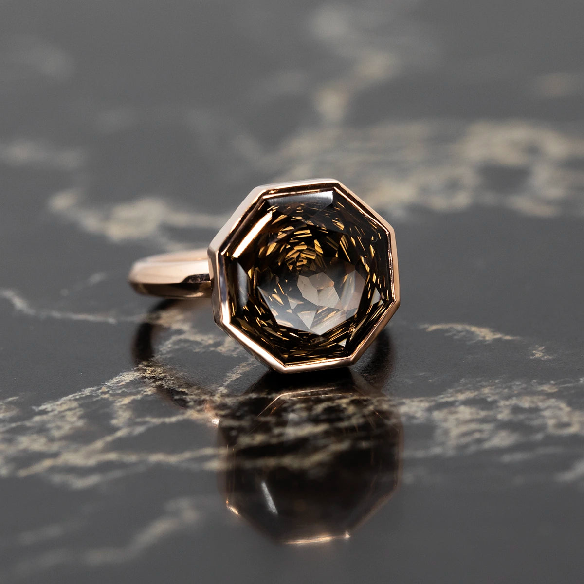 Rose gold cocktail ring with a Brazilian smoky quartz, featuring a round-octagon cut, displayed on a bold background.