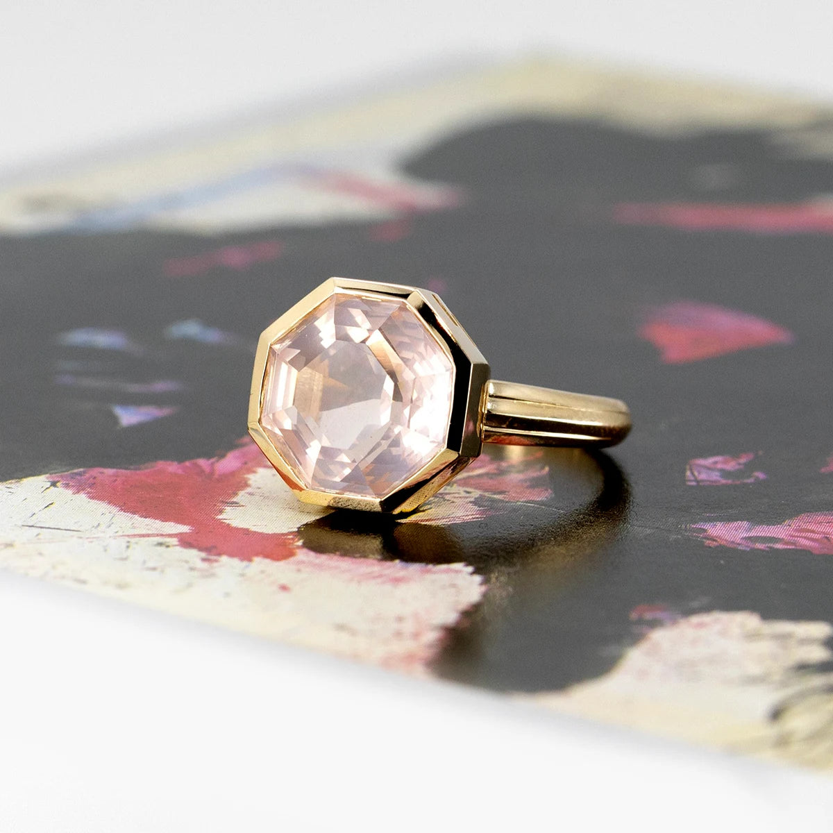 Bijou Rose Quartz Yellow Gold Ring, featuring a unique contemporary design, photographed on a colorful surface.