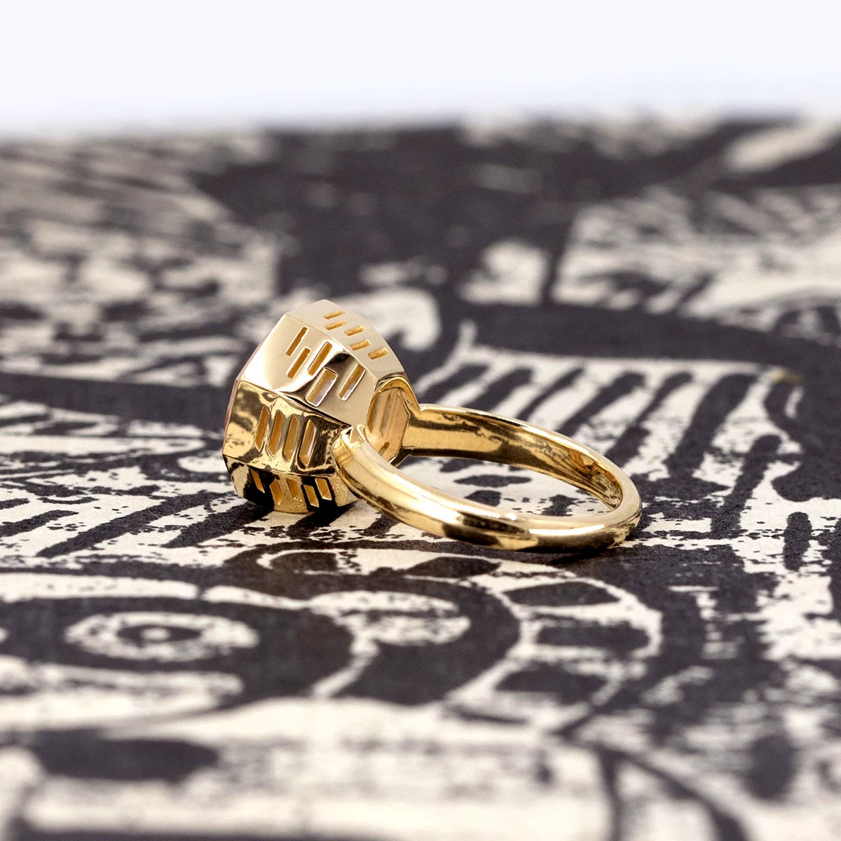Side view of a statement rose quartz cocktail ring in yellow gold, part of the Fancy Edgy collection by Bena Jewelry, photographed on a dark surface.