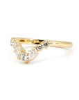 Side view of a yellow gold diamond wedding band by Bena Jewelry, highlighting its sleek profile with round and pear-shaped diamonds. Photographed against a white background.