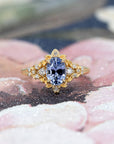 Sky Bloom Sapphire Ring on soft-toned background – The luminous blue sapphire and floral gold details contrast beautifully with the subtle backdrop.