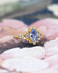 Close-up of engagement ring on dark background – The intricate floral gold setting highlights the brilliance of the sapphire in a dramatic way.