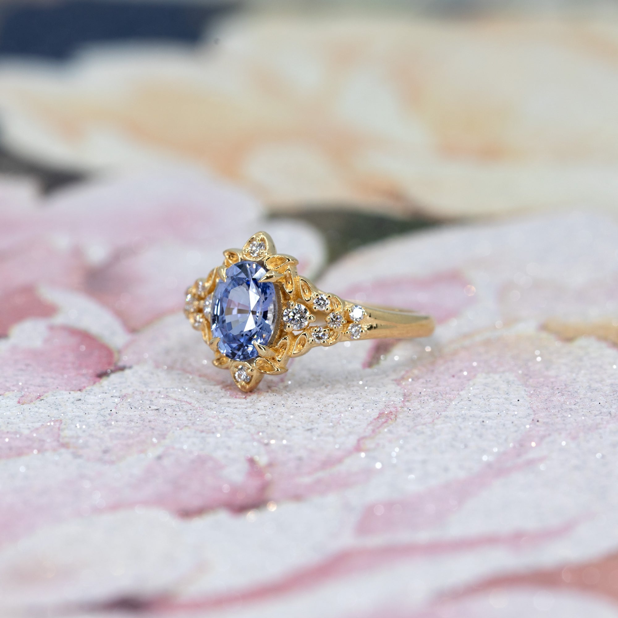 y Bloom Oval Sapphire Ring worn on hand, close-up – A unique engagement ring featuring a sky-blue oval sapphire with an organic, floral-inspired gold design. Handmade by Bena Jewelry in Montreal.