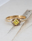 Creative flatlay of a contemporary Bena Jewelry ring with a yellow Asscher diamond and brown halo, made in Montreal, displayed on a colorful background for visual impact.