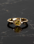 Elegant lighting highlights the structure of this 14k gold ring by Bena Jewelry, crafted in Montreal with a vivid yellow Asscher diamond and brown diamond halo, on a black surface.