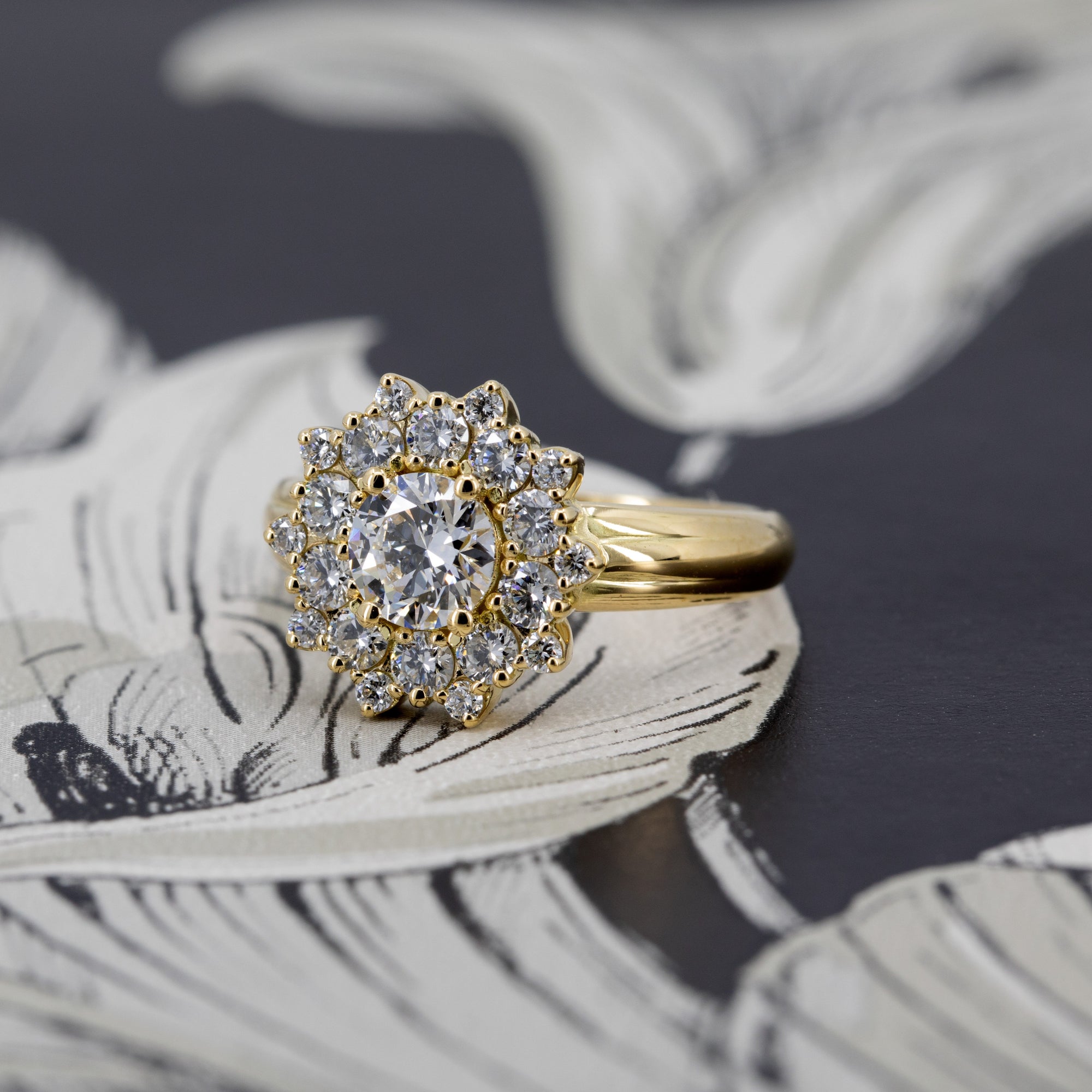 Diamond halo ring in 14k yellow gold on black surface, crafted by Canadian fine jewelry designer Bena Jewelry – engagement or statement piece