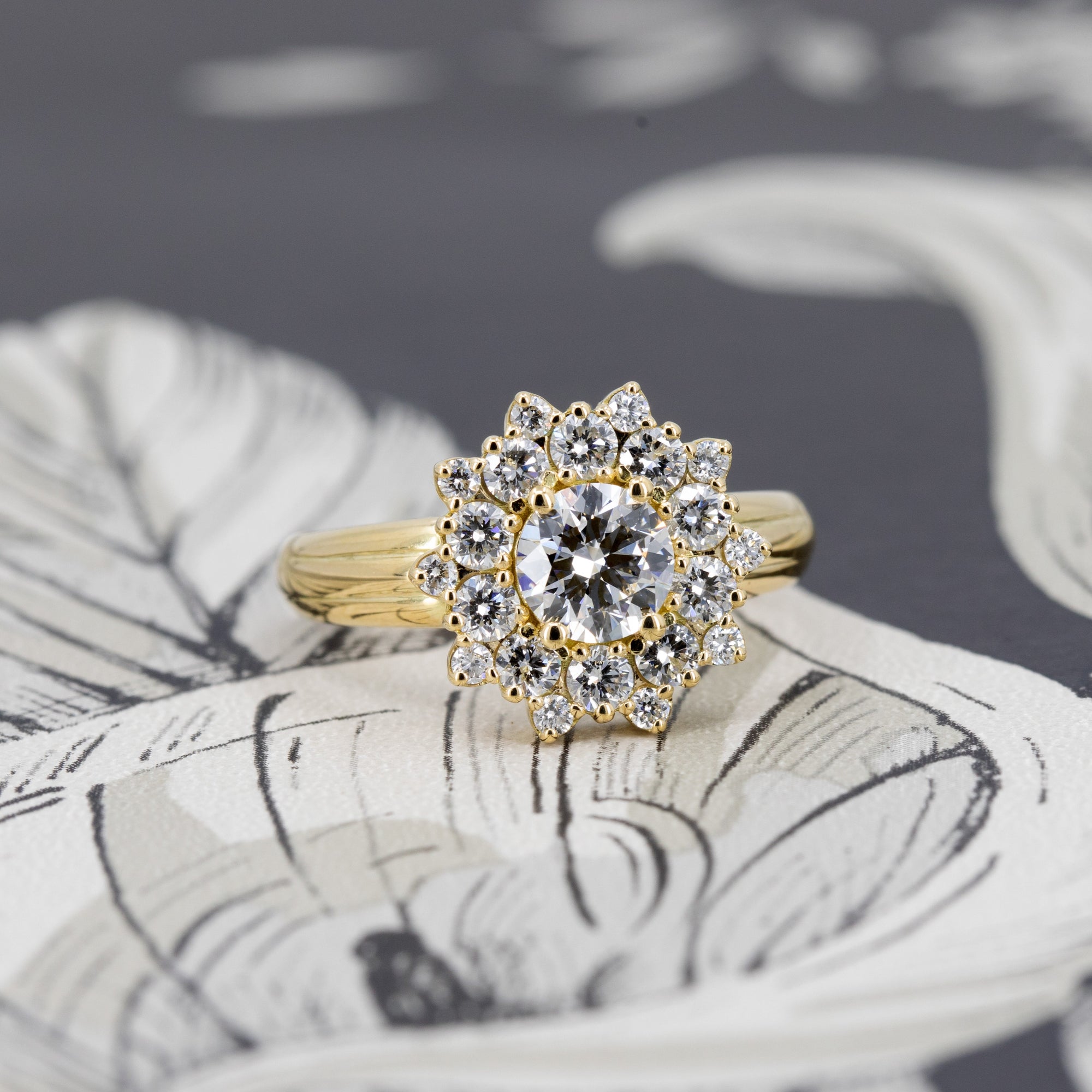 Soleil ring in yellow gold with white diamonds, glowing against dark background – bold floral halo design by Bena Jewelry, Montreal