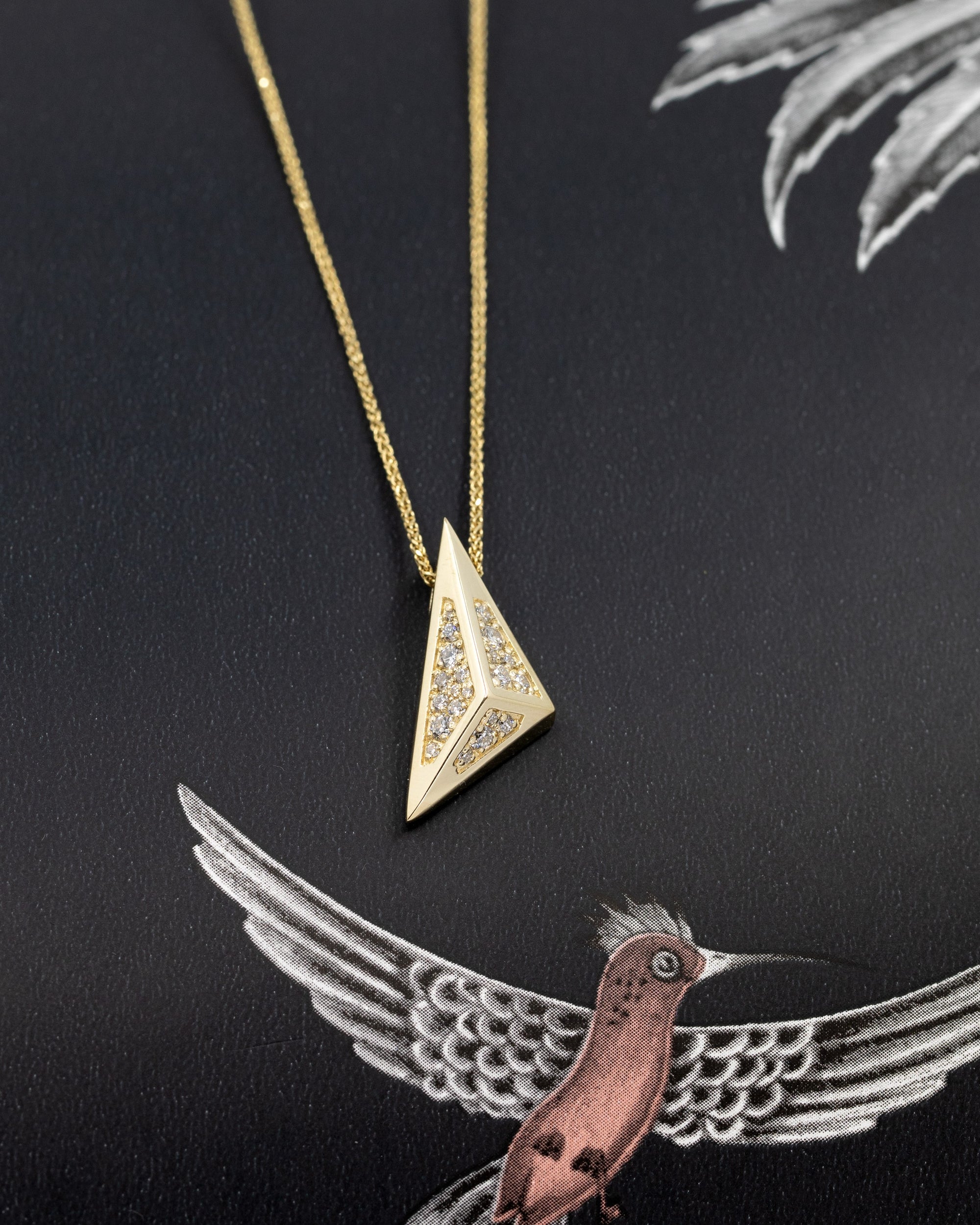 Edgy Pyramidal Pendant in yellow gold with diamond paving, shown against a striking black background, emphasizing its modern, geometric design by Bena Jewelry.