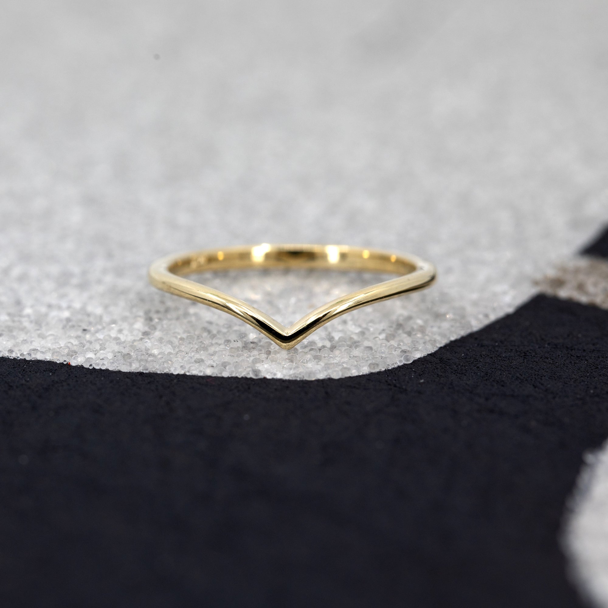 Minimalist V-shaped gold band with a polished finish, handmade in Montreal, set against a deep black background.