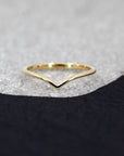 Minimalist V-shaped gold band with a polished finish, handmade in Montreal, set against a deep black background.