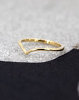 Velar Band by Bena Jewelry, a sleek V-shaped yellow gold wedding ring, showcased on a black background for contrast.