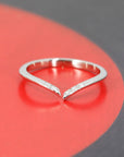 A delicate white gold wedding band with natural diamonds, displayed on a vibrant red circular backdrop, emphasizing its sleek design and the brilliance of the diamonds. A design from Bena Jewelry, an independent Canadian brand.