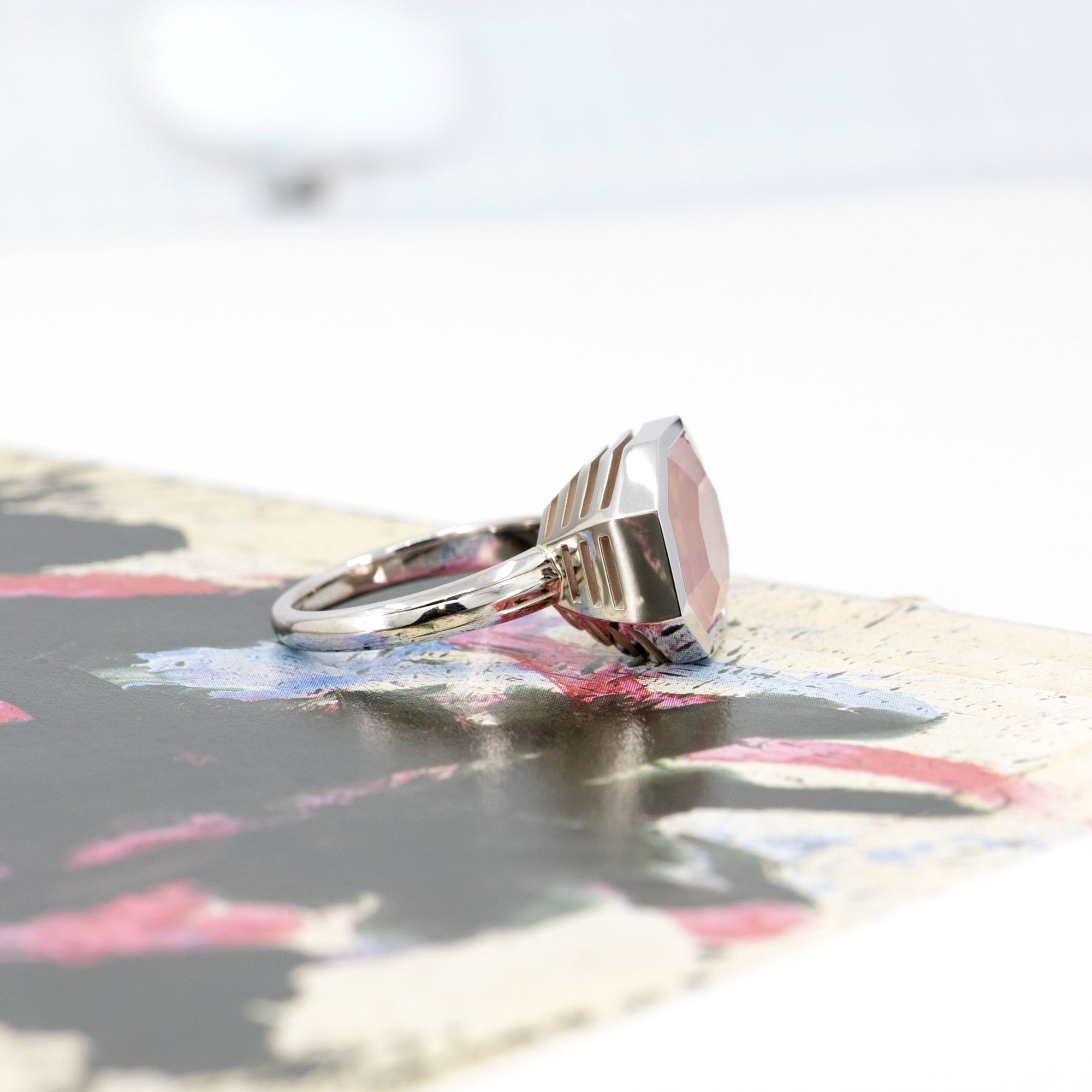 Side view of the white gold cocktail ring with a candy-pink rose quartz, highlighted on a bold background. Fine jewelry made in Montreal.