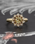 Close-up of the Soleil yellow diamond ring with a brown and white diamond halo, set in yellow gold, shown against a dark backdrop by Bena Jewelry.