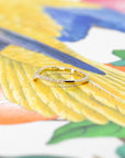 Elegant yellow gold wedding band with a gentle curve and sparkling diamonds, shown on a vibrant background. Designed by Bena Jewelry in Montreal.