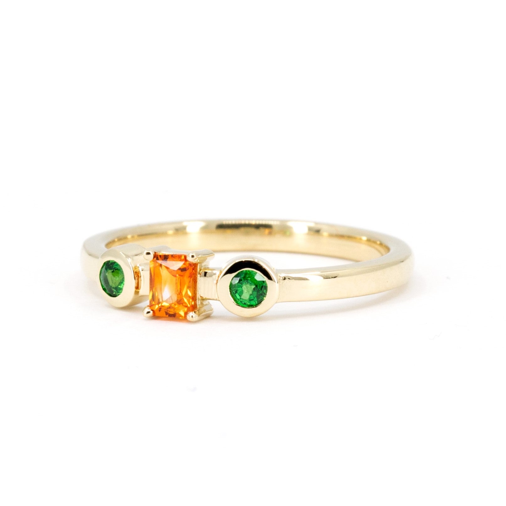 Yellow gold ring with a baguette-cut orange sapphire and two green garnet side stones, handcrafted by Bena Jewelry in Montreal, Canada.