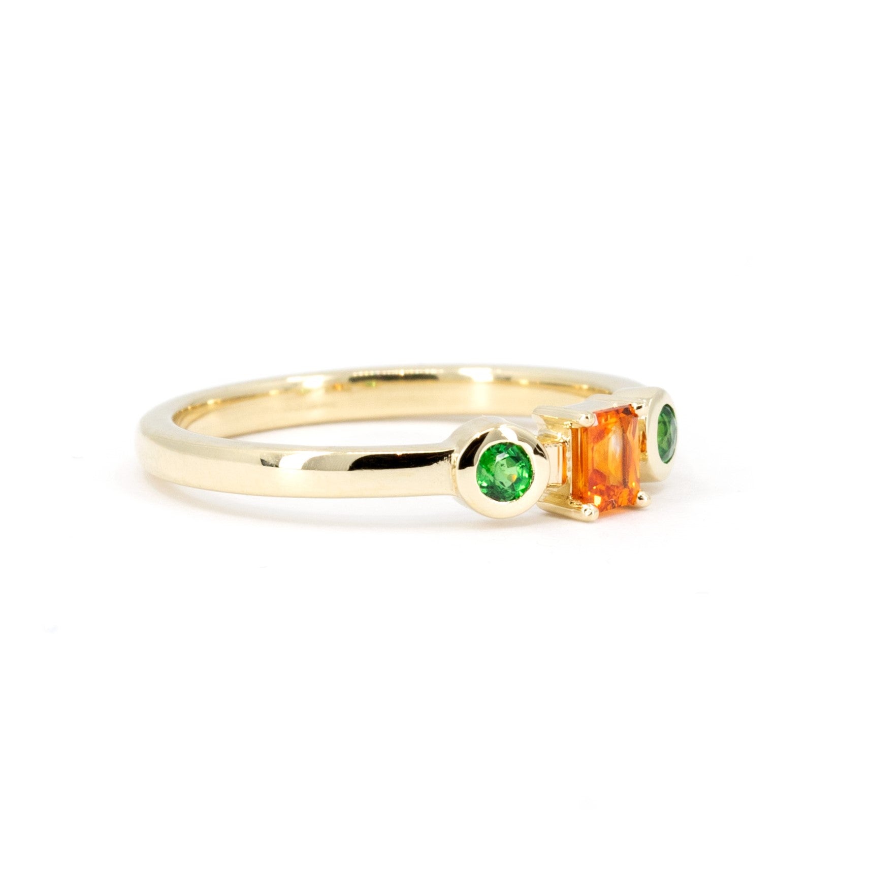 Custom designer ring in yellow gold featuring a vibrant orange sapphire and green garnets, made by Bena Jewelry in Montreal.