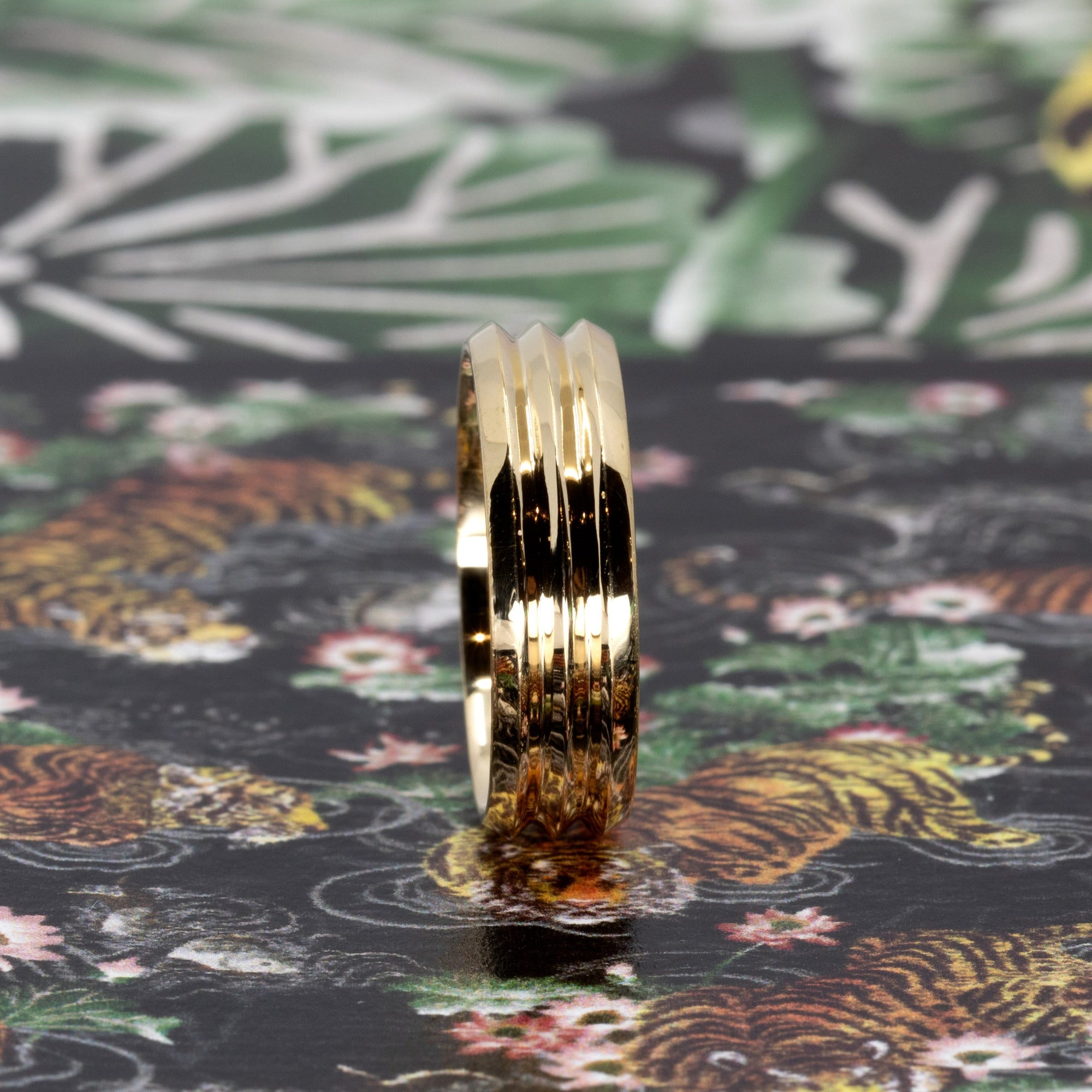 Trois Vagues yellow gold men's wedding band, displayed with a contemporary colored backdrop, emphasizing the sleek lines. Made in by Bena Jewelry Montreal.
