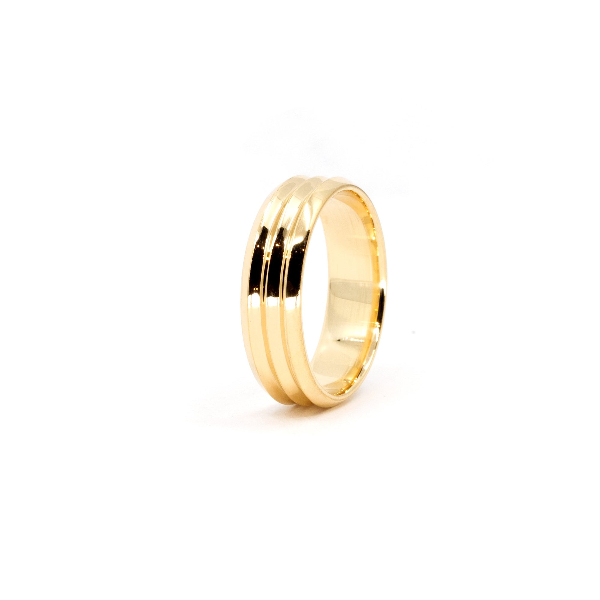 Side view of the Trois Vagues men's wedding band in yellow gold, highlighting the smooth design and central lines, against a pure white background.