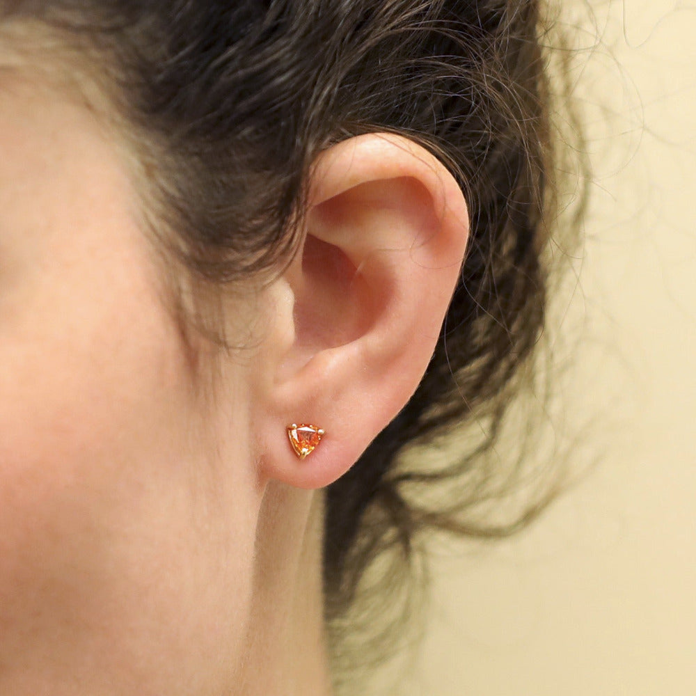 Girl wearing trillion orange sapphire yellow gold stud earrings bena jewelry