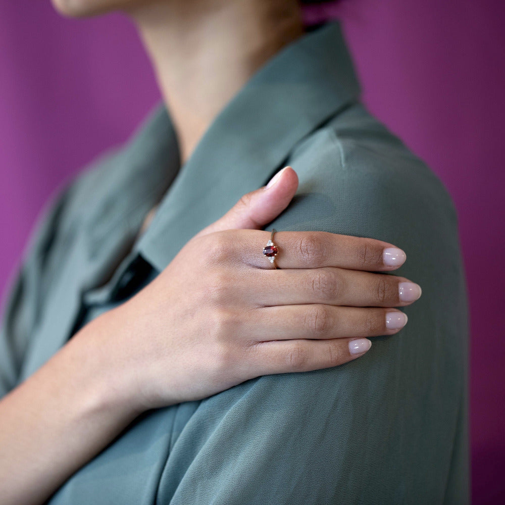 Elegant bridal ring featuring a pyrope garnet and diamonds in yellow gold Désir Pyrope Garnet Ring by Bena Jewelry worn by a woman on her shoulder custom bridal jewelry from Montreal.