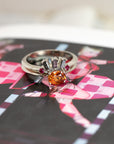 orange garnet engagement ring and salt pepper diamond wedding band made in montreal on a multi color background