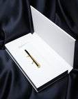 A solid gold ring with lots of character is seen placed in its box. The jewel consists of a long, shapely block of gold that runs the full width of the fist and is worn on two fingers with a comfortable double band. It's by Montreal-based designer Bena Jewelry, who creates modern, elegant, gender-neutral jewelry that reflects light in a unique way.