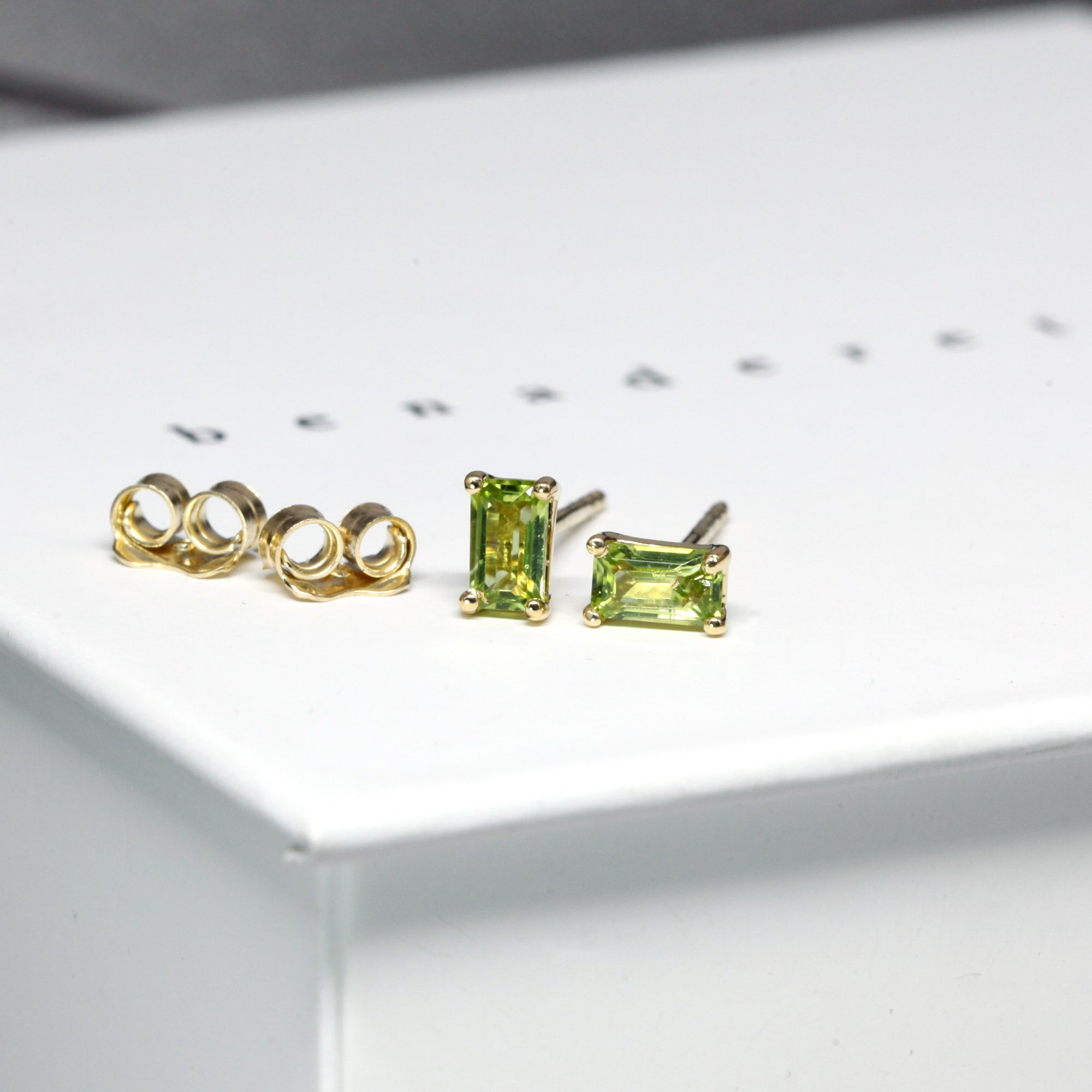 front view of peridot baguette jewelry gemstone stud earrings bena jewelry montreal specialist vivid green gemstone earrings custom made fine jewelry montreal green gemstone jewels earrings bena earrings