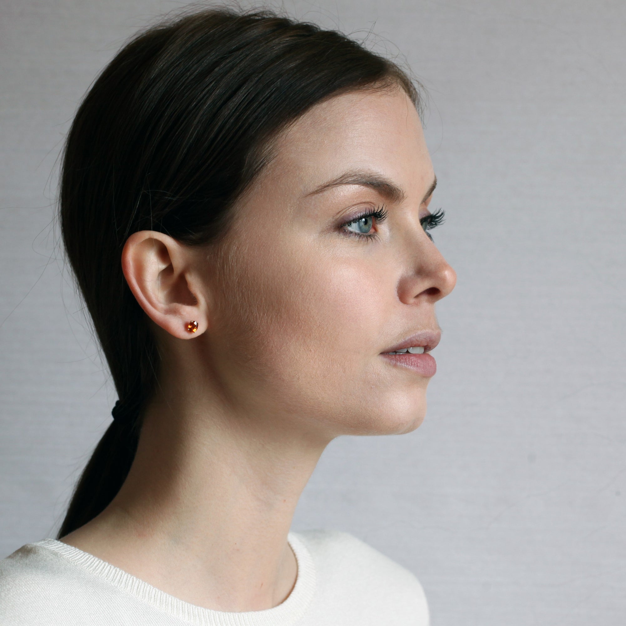 girl wearing spessartite garnet gemstone stud earrings montreal made yellow gold fine jewelry handmade in montreal oval shape vivid natural orange small earrings studs gems bridal jewelry color gemstone specialist