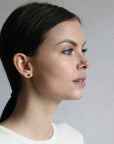 girl wearing spessartite garnet gemstone stud earrings montreal made yellow gold fine jewelry handmade in montreal oval shape vivid natural orange small earrings studs gems bridal jewelry color gemstone specialist