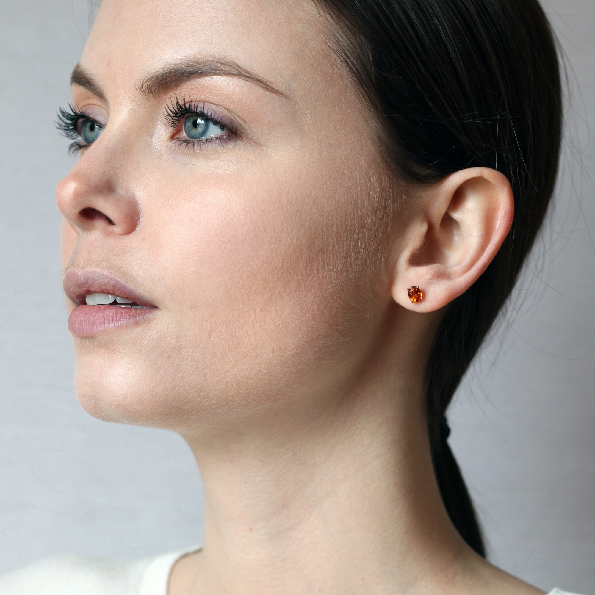 girl wearing a spessartite garnet gemstone stud earrings bena jewelry montreal made in canada oval shape garnet yellow gold stud earrings color gems bridal jewelry custom made in montreal fine jewelry ethical jewelry studio little italy montreal fine jewelry designer
