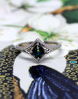 Vivid tones surround this striking cushion-cut teal sapphire ring, capturing the elegance and modern aesthetic of Bena Jewelry.
