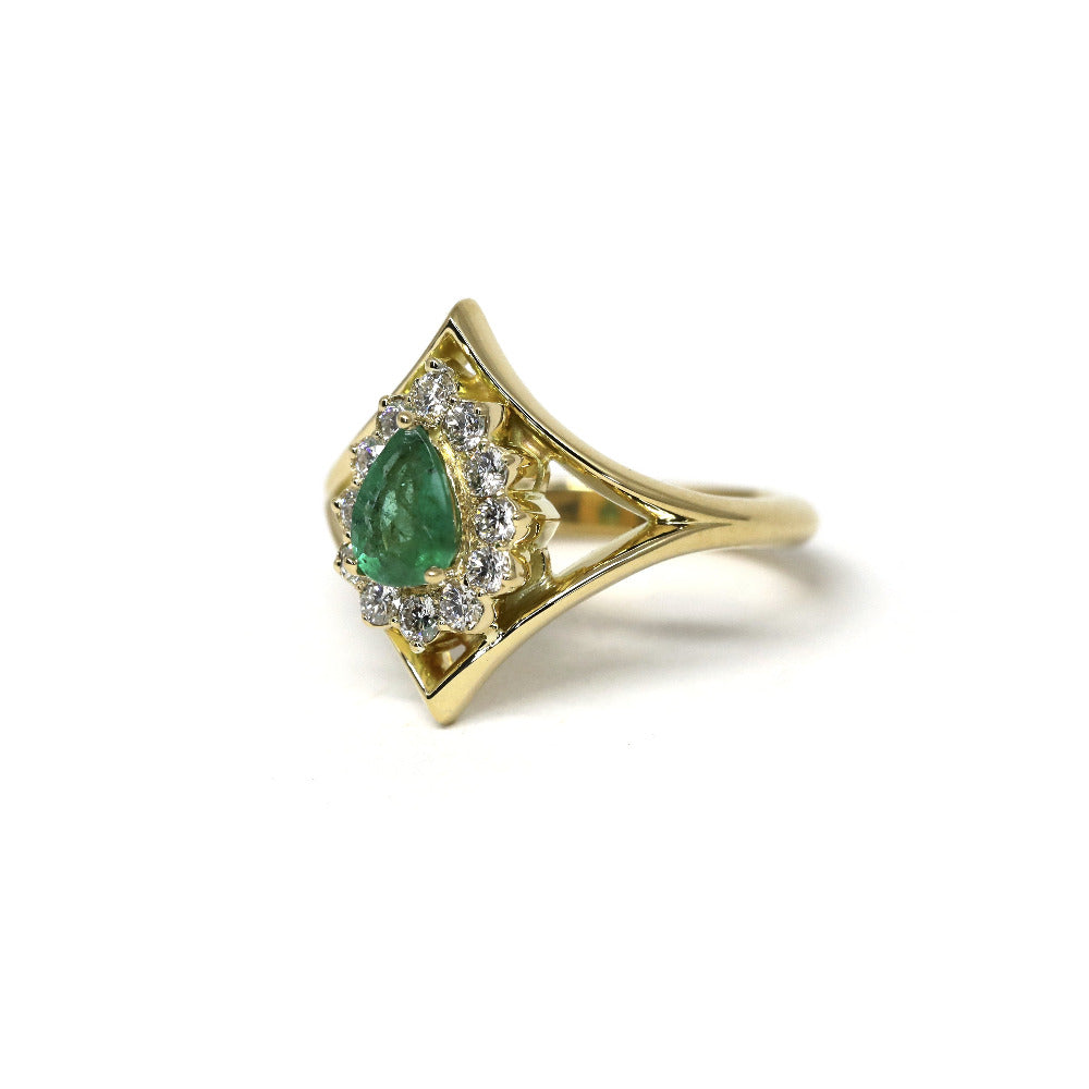 Side view emphasizing the ring's yellow gold band and intricate halo design around the emerald. A bespoke creation crafted by Bena Jewelry in Montreal, Canada.