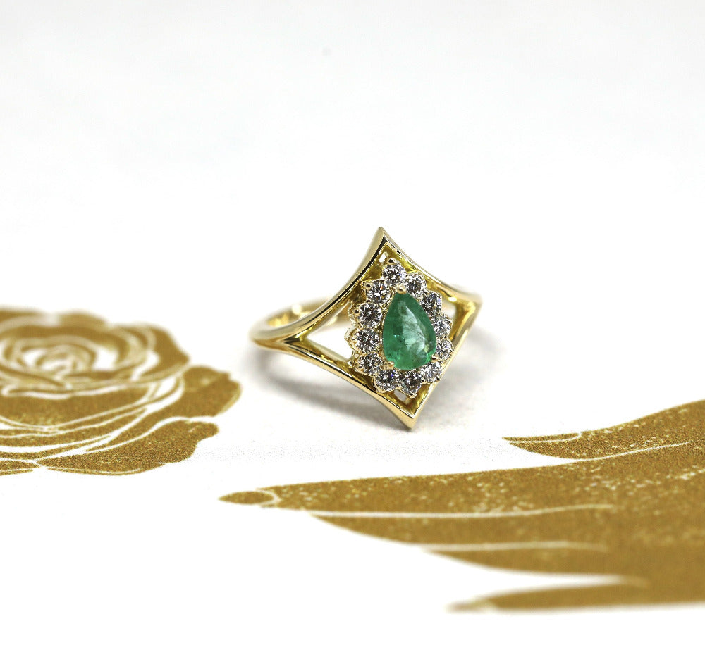 Close-up of the emerald centerpiece, with the delicate halo and polished yellow gold band. Made in Montreal, Canada, by independent jeweler Bena Jewelry.