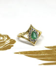 Close-up of the emerald centerpiece, with the delicate halo and polished yellow gold band. Made in Montreal, Canada, by independent jeweler Bena Jewelry.