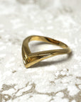 Unique yellow gold statement ring with angular curves, Adorn Ring by Bena Jewelry, displayed on a black matte background, modern edgy jewelry crafted in Montreal.