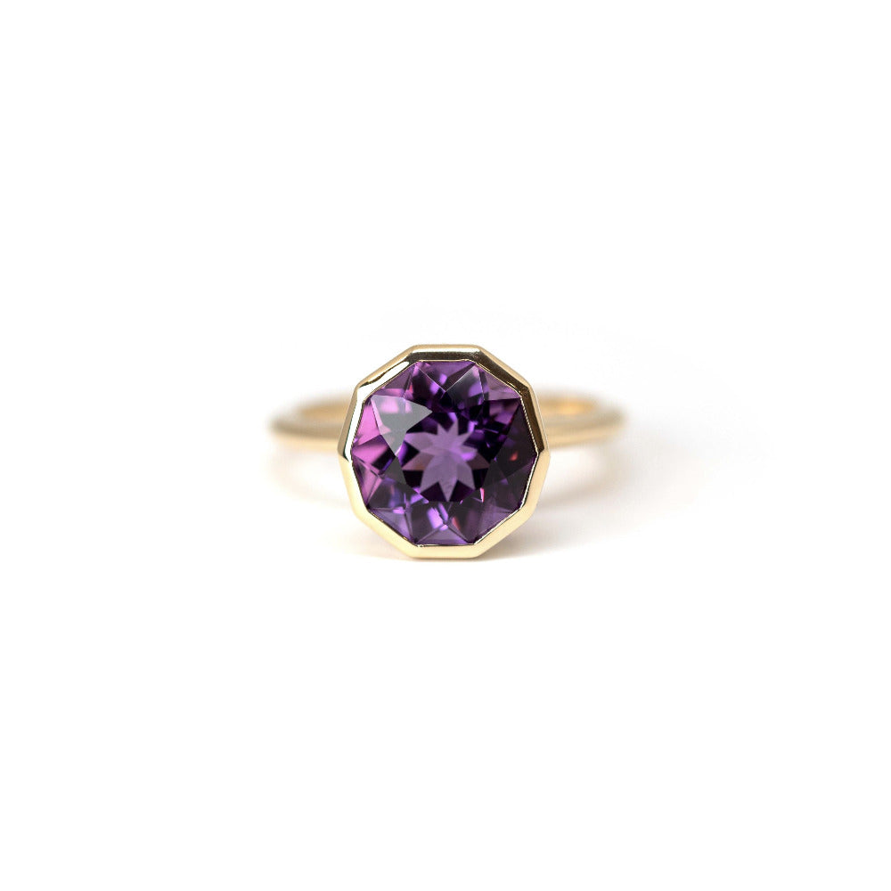 Front view of Bijou Round Amethyst Ring with violet gemstone and pink undertones, crafted by Bena Jewelry in Montreal, displayed on a minimalist white surface.