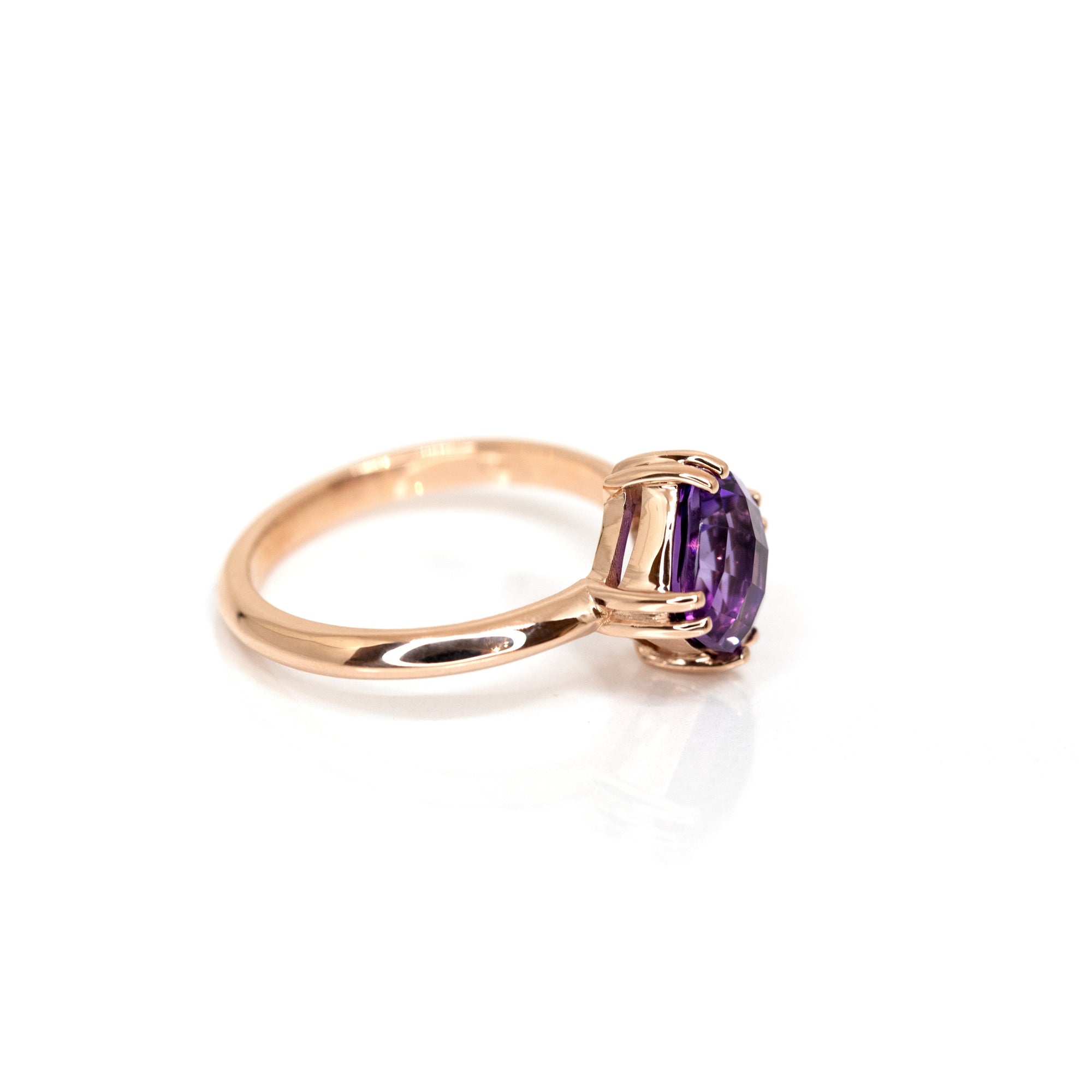 Close-up of a cushion-cut amethyst ring, showcasing its checkered facets and rich violet hue. A refined rose gold design by Bena Jewelry.