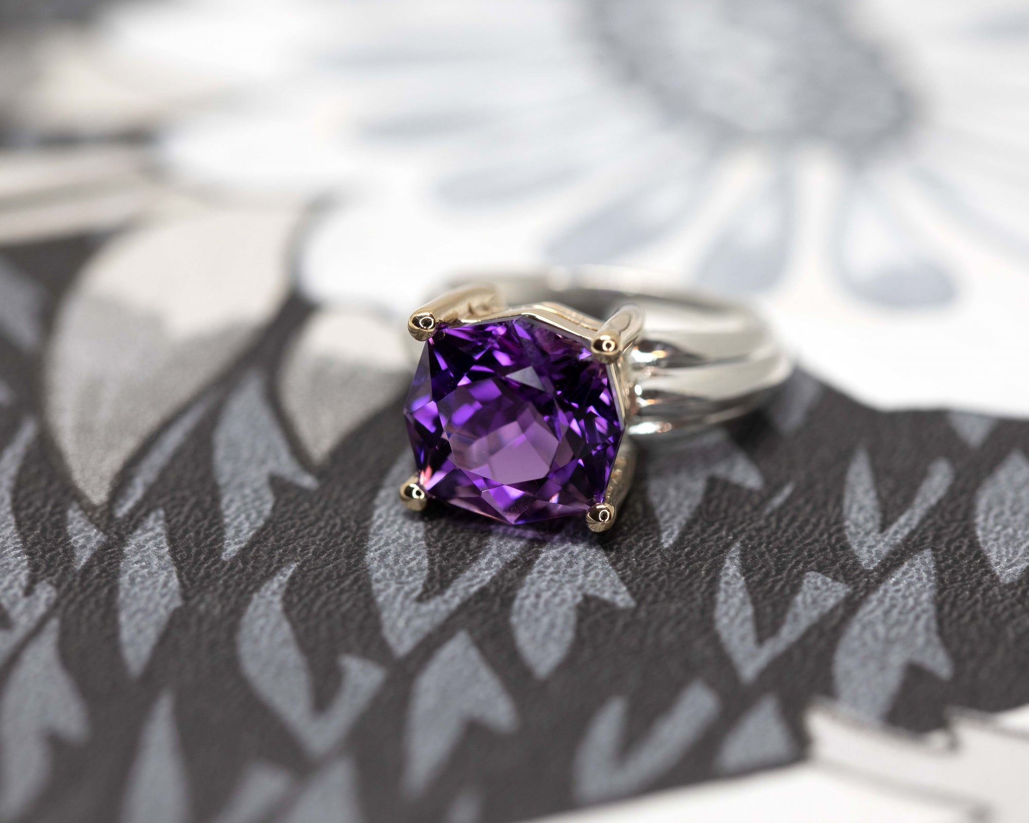 Side angle on gray background: Displays the depth of the amethyst's rich purple color and the sleek design of the silver and gold band.