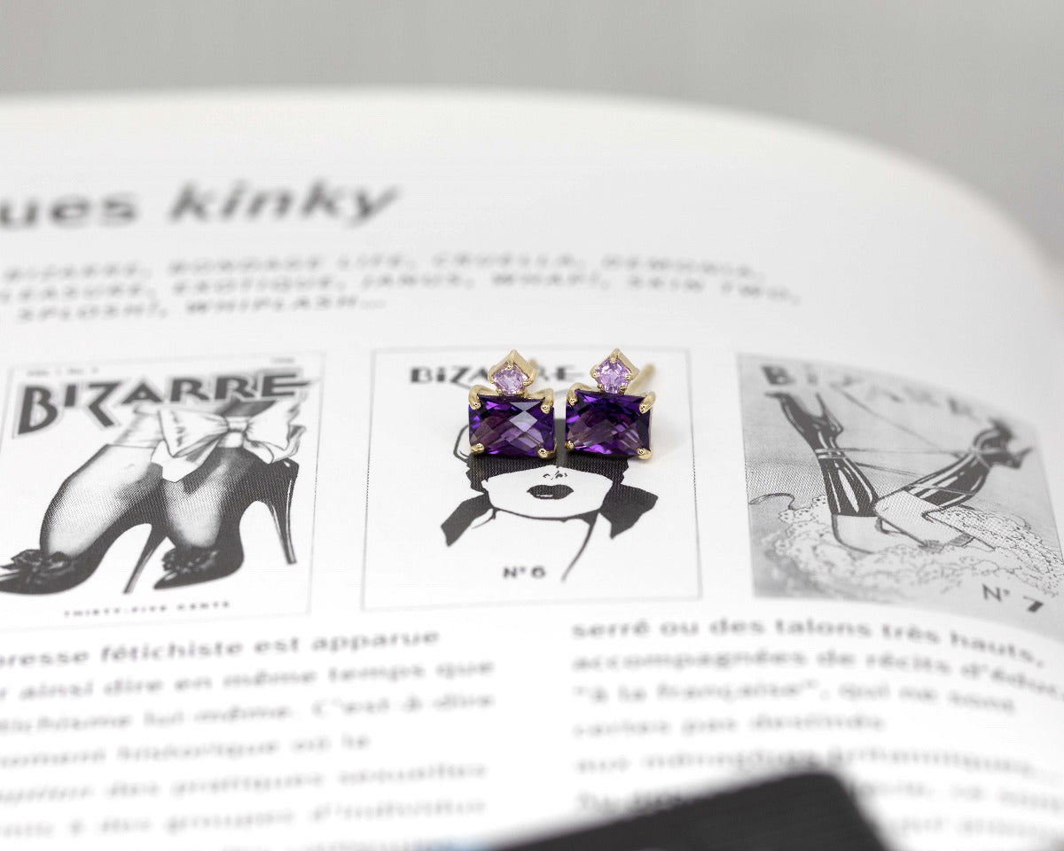 pair of amethyst and pink sapphire gemstone studs earings made in montreal by bena jewelry on a news paper