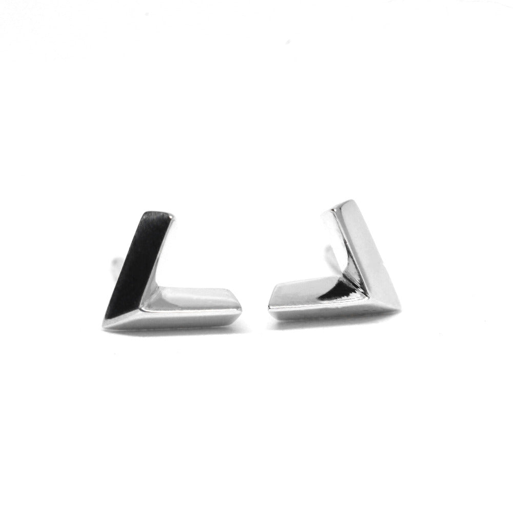 White gold arrow-shaped studs displayed on a white surface. Their edgy, minimalist design reflects modern unisex style, crafted in Montreal by Bena Jewelry, a leader in contemporary fine jewelry.