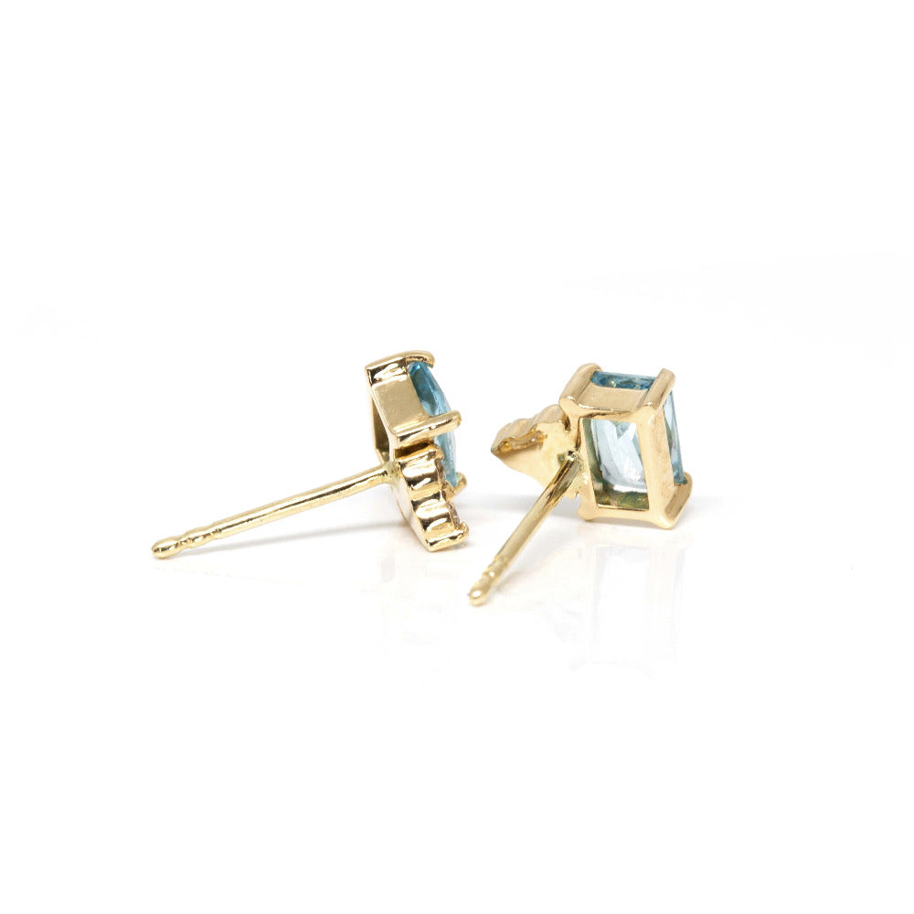 Close-up of natural zircons in a vibrant sky-blue hue paired with sparkling diamonds, set in yellow gold prongs.