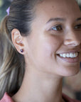 Worn by a model (portrait): A young woman wears the Amethyst & Pink Studs Earrings, demonstrating their elegant proportions and striking gemstone combination.
