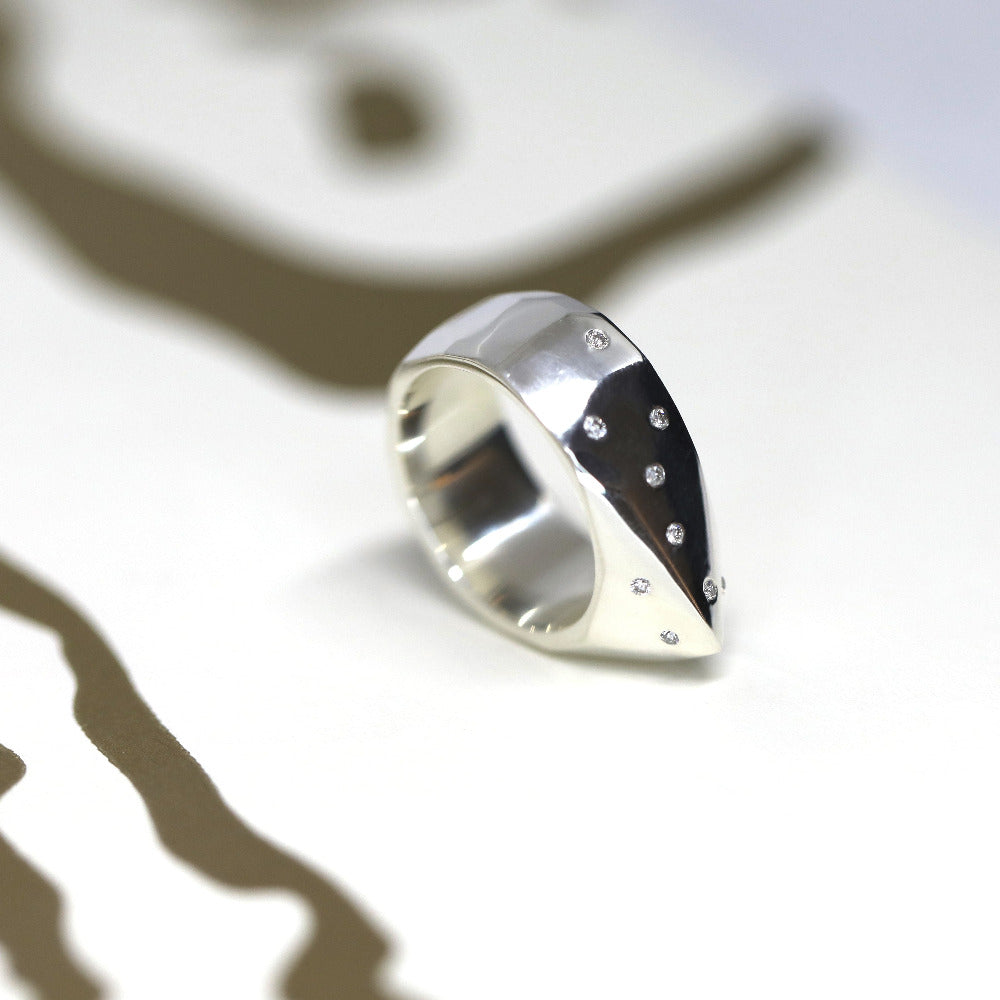 The Alp Ring’s bold presence shines in white gold, featuring smooth organic curves and shimmering diamond pavé. A modern unisex statement, made in Montreal.