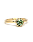 Minimalist green garnet engagement ring in yellow gold, Bezel Set Demantoide by Bena Jewelry, displayed on a clean white background. Custom-made in Montreal.