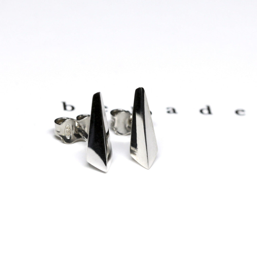 White gold Blade stud earrings by Bena Jewelry, showcased on a sleek black matte background. The sharp geometric design contrasts beautifully against the white surface, highlighting their bold and contemporary appeal. Designed in Montreal, made in Canada.