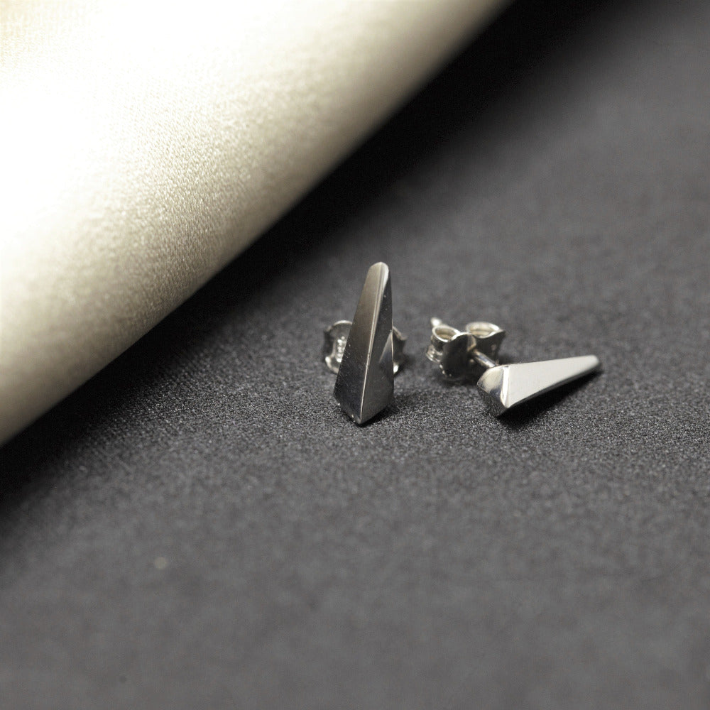 Bena Jewelry's Blade earrings in white gold, photographed on a luxurious grey slick surface. The modern unisex design combines sophistication with an edgy aesthetic. Handmade in Montreal, Canada."